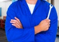 Mechanic standing with arms crossed holding wrench Royalty Free Stock Photo