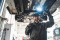Mechanic standing under a car on a lift and holding a flashlight Royalty Free Stock Photo