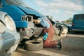 Mechanic stuck head under the hood, car junkyard Royalty Free Stock Photo