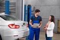 Woman talking to man in overalls about car repair Royalty Free Stock Photo