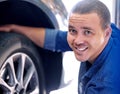 Mechanic, tire change and happy man car service assistant in automobile shop or road side assistance. Wheel safety