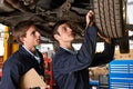 Mechanic And Trainee Working On Car Together