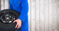 Mechanic with tyre against blurry wood panel Royalty Free Stock Photo