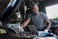 Mechanic using compute for Diagnostic  machine tools ready to be used with car. Car mechanic using a computer laptop to diagnosing Royalty Free Stock Photo