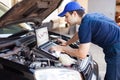 Mechanic using a laptop computer to check a car engine Royalty Free Stock Photo