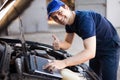 Mechanic using a laptop computer to check a car engine Royalty Free Stock Photo