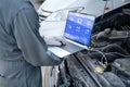 Mechanic using a laptop computer to check collect information during work a car engine. service maintenance of industrial to Royalty Free Stock Photo