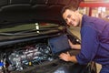 Mechanic Using Laptop While Examining Car Engine