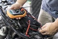Mechanic using multimeter to check the voltage level on motorcycle battery at garage, Maintenance and repair concept