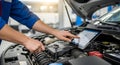 A mechanic using a tablet to diagnose a car engine Royalty Free Stock Photo