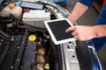 Mechanic using tablet to fix car