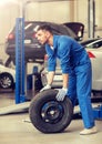 Mechanic with wheel tire at car workshop Royalty Free Stock Photo