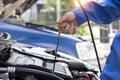 Mechanic at work in his garage auto check up and car service shop concept. Close up hand mechanic checking oil level in a engine Royalty Free Stock Photo