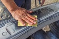 Mechanic worker repairman sanding polishing car bumper and preparing bumper for painting during repair Royalty Free Stock Photo