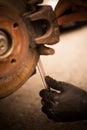 Mechanic working at a car worn and rusty brake disk and caliper Royalty Free Stock Photo