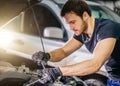 Mechanic working under car hood in repair garage