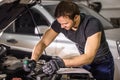 Mechanic working under car hood in repair garage