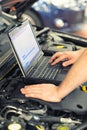 Mechanic in a workshop checks and checks the electronics of the car - software update with a modern computer Royalty Free Stock Photo