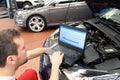 Mechanic in a workshop checks and checks the electronics of the car - software update with a modern computer Royalty Free Stock Photo