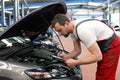 mechanic in a workshop checks and inspects a vehicle for defects Royalty Free Stock Photo