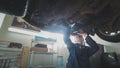 Mechanical auto workshop - a mechanic checks the suspension of car, wide angle