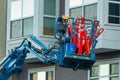 Mechanical crane or cherry picker filled with orange reflective traffic cones in an dense urban setting in afternoon shade