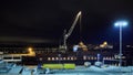 Mechanical hydraulic clamshell grabbers loading coal on ship at night.