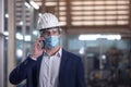 Mechanical worker with mask talking on the phone in a factory
