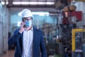 Mechanical worker with mask talking on the phone in a factory