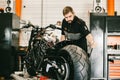 Mechanician changing motorcycle wheel in bike repair shop. Royalty Free Stock Photo