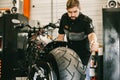 Mechanician changing motorcycle wheel in bike repair shop. Royalty Free Stock Photo