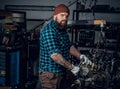 Mechanicl inspecting engine of a car in a garage.