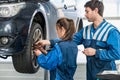 Mechanics Changing Tire From Suspended Car At Garage Royalty Free Stock Photo