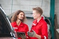 Mechanics in uniform with tablets working in auto service, Young Caucasian car mechanics with a checklist, Technician checking Royalty Free Stock Photo