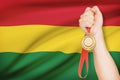 Medal in hand with flag on background - Plurinational State of Bolivia