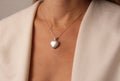 Medallion pendant in shape of heart made of silver on chain hangs around neck, on chest of a young girl. Love and romance, Royalty Free Stock Photo