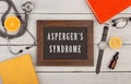 blackboard with text & x22;Asperger& x27;s syndrome& x22;, books, stethoscope, eyeglasses and watch