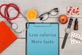 clipboard with text & x22;Less calories more taste& x22;, book, pills, eyeglasses, watch, fruit and stethoscop Royalty Free Stock Photo
