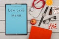clipboard with text & x22;Low carb menu& x22;, stethoscope, book, pills, fruits, eyeglasses and watch Royalty Free Stock Photo