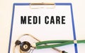 MEDI CARE- text on medical folder with documents and stethoscope on white background