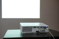 Media projector standing on table, white screen on the wall, nobody Royalty Free Stock Photo