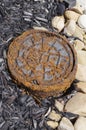 Rusty cover on water valve with mulch and stone Royalty Free Stock Photo