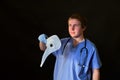 A medic holds a plague doctor mask on a dark background