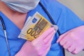 A medic in protective gloves puts money in the pocket of a blue medical uniform, close-up