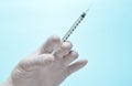 Medic& x27;s hand with white latex gloves holds syringe with needle on blue background. Medical concept. Royalty Free Stock Photo