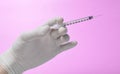 Medic& x27;s hand with white latex gloves holds syringe with needle on blue background. Medical concept. Royalty Free Stock Photo