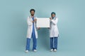 Medical Ad. Smiling Arab Male And Female Doctor Holding Blank Placard, Royalty Free Stock Photo