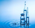 Medical ampoules and botttle on the blue water background with splash Royalty Free Stock Photo