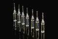 Medical ampoules for injection, isolated on black background with reflection. Ampoules with vaccine, medicine, collagen Royalty Free Stock Photo