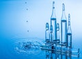 Medical ampoules and syringe on blue water background with splash and drops Royalty Free Stock Photo